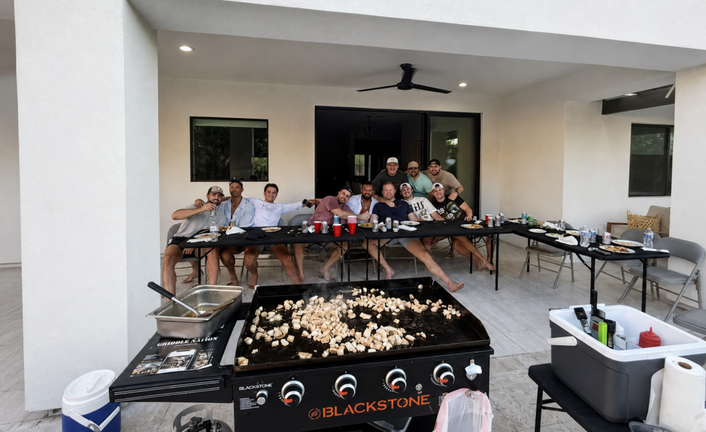 Hibachi chef and guests posing beside the mobile Blackstone grill