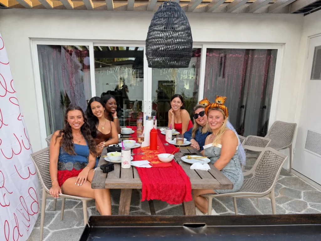 Women gathered around a red table for an outdoor hibachi meal