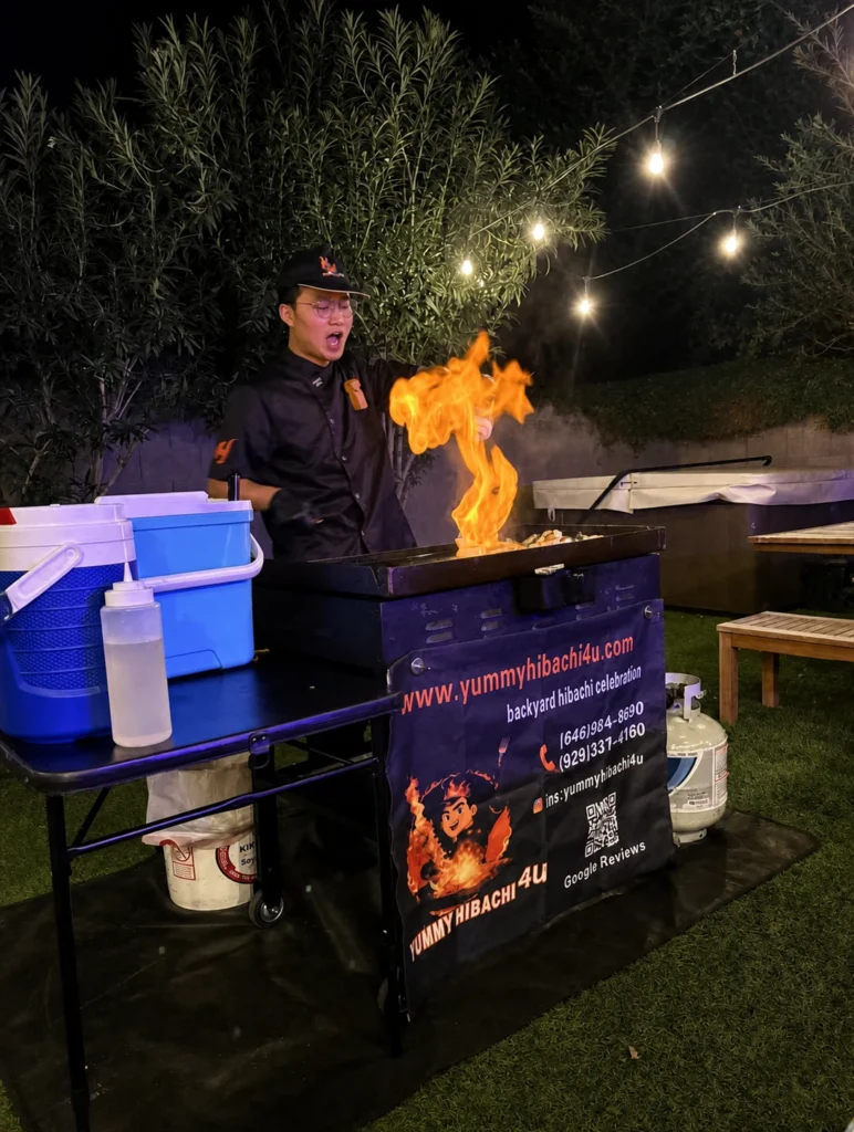 Hibachi chef performing with flames beneath patio lights