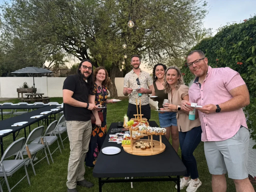 Guests posing beside a sushi display at an outdoor party
