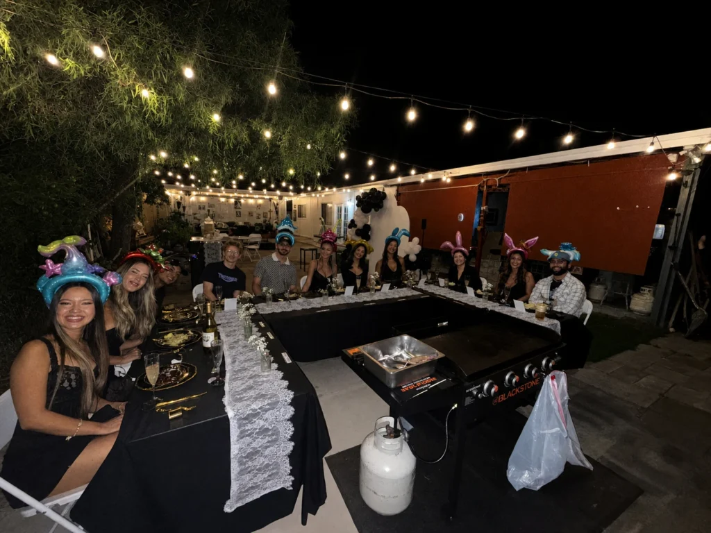 Guests wearing balloon hats around a nighttime hibachi table
