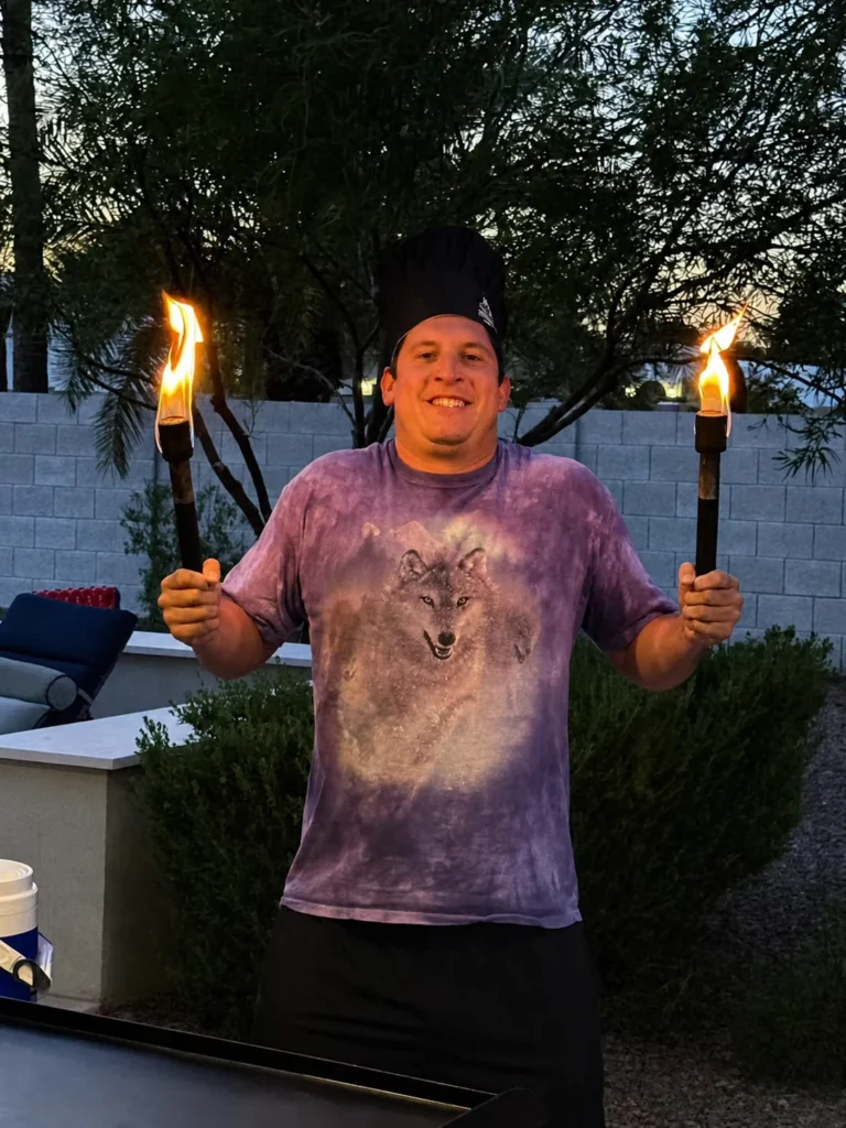 Guest holding two flaming torches beside the hibachi grill