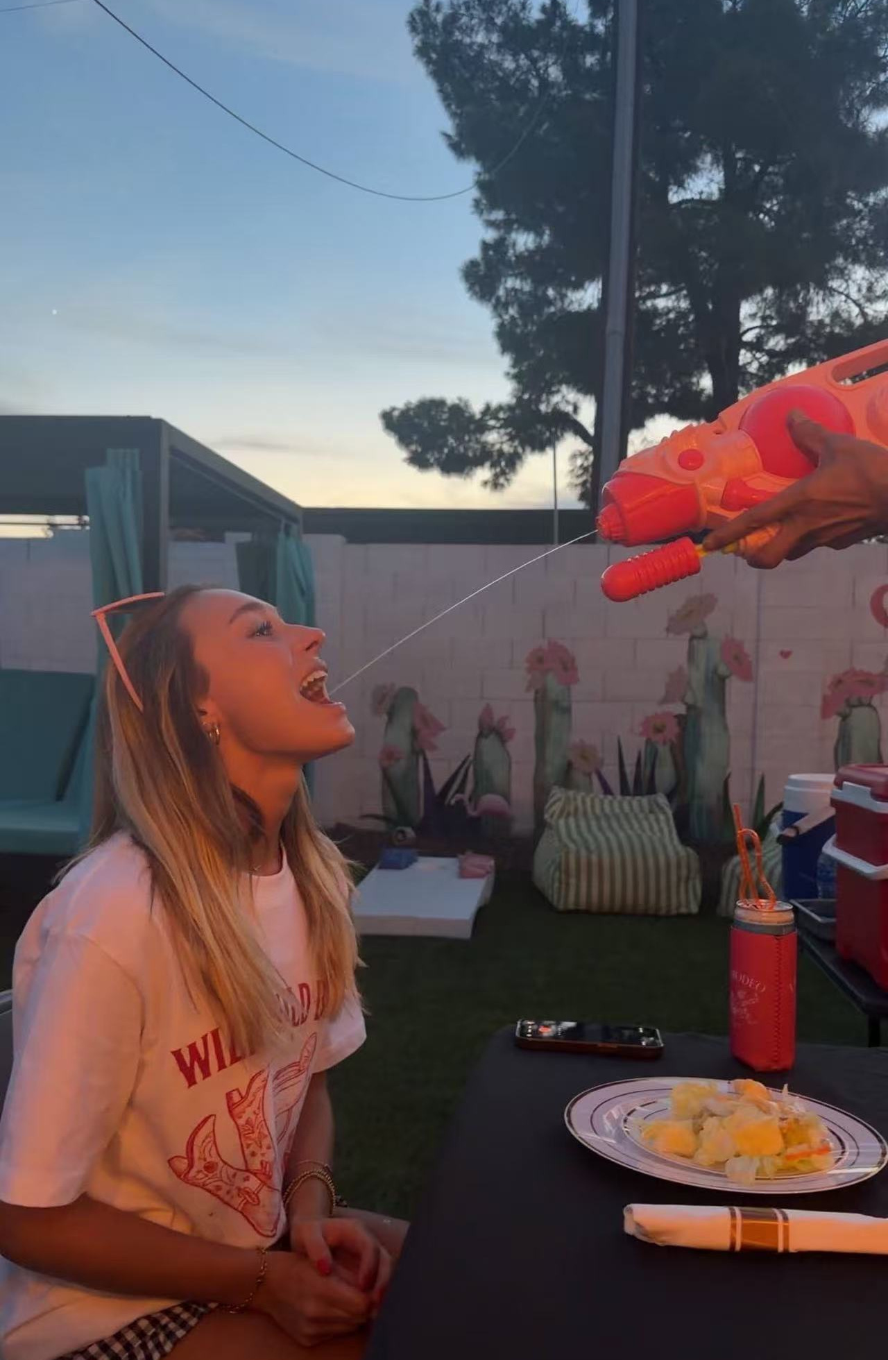 Guest enjoying sake from a water gun at a backyard hibachi party